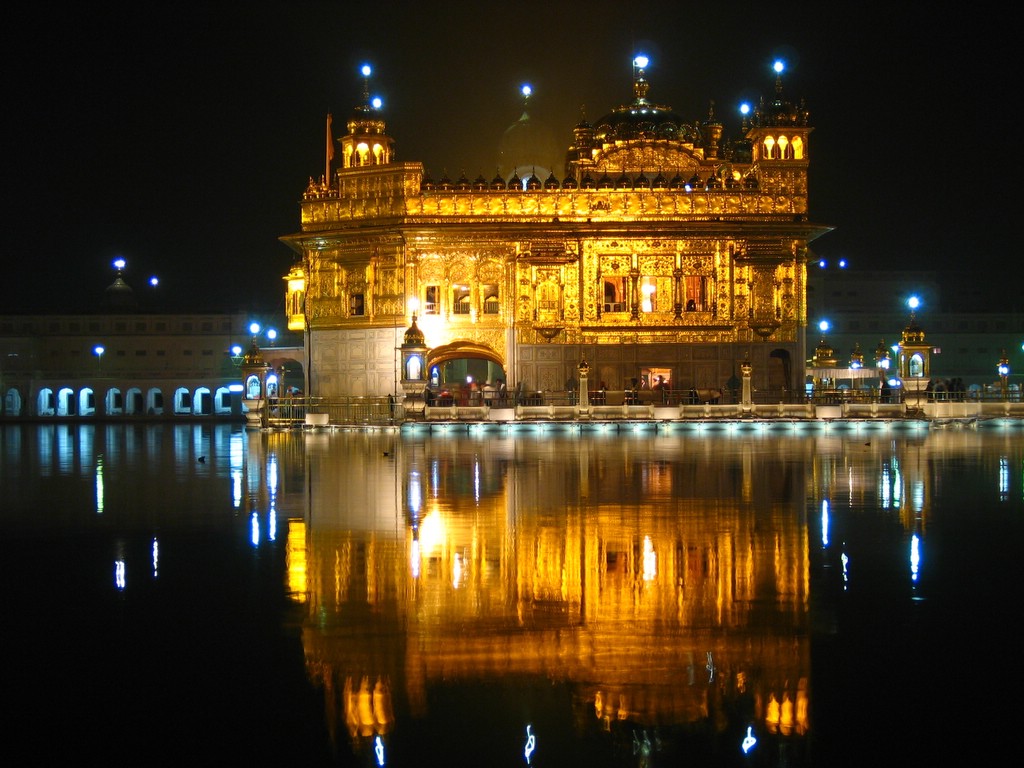 Harmandir Sahib glowing above the sacred pool at night